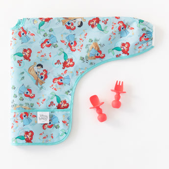 A colorful baby bib with Ariel is paired with Bumkins Silicone Chewtensils®: Red on a white background.