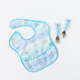 Bumkins Spoon + Fork: Stitch sits by a pastel blue Stitch-themed bib on a white background.