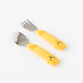 Bumkins Spoon + Fork: Winnie the Pooh lays angled on a white background, with focus on the bear-shaped handles.