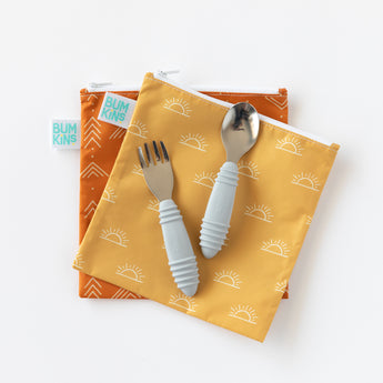 Two Bumkins zippered pouches with sun & chevron hold a Spoon + Fork: Gray toddler set for self-feeding on a white background.