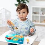 Child in a pastel bib holding a Bumkins Spoon + Fork: Tangerine.