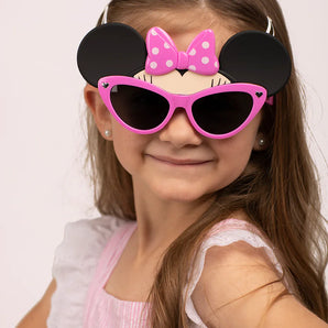 A child beams in her pink dress with Sunstaches Lil Characters Minnie Mouse sunglasses, offering cute Disney style and kids UV protection.