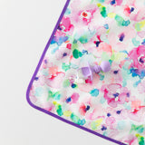 A Bumkins Silicone Chewtensils®: Lavender lays on top of a floral mat with yogurt splatter on a white background.
