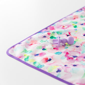 Close-up of a baby spoon with food on top of a Bumkins Splat Mat: Watercolor on a white background.