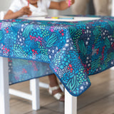 A child coloring at a table with a Bumkins Splat Mat: Animal Prints draped over the top.
