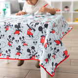 A child draws on paper at a table with a Bumkins Splat Mat featuring Mickey Mouse in his iconic red shorts.