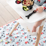 Child in high chair eating oatmeal, raspberries, cucumber with a Mickey Mouse spoon on Bumkins machine-washable Splat Mat: Mickey Mouse.
