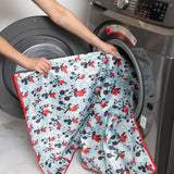 Placing a waterproof Bumkins Splat Mat: Mickey Mouse into the front-loading washing machine.