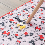 Scrambled eggs and a Mickey Mouse fork sit on a Bumkins Splat Mat: Minnie Mouse, under a wooden table leg on the floor. 