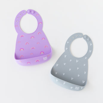 Bumkins Silicone Bib 2 Pack: Hearts and Rainbows lays flat on a white background.