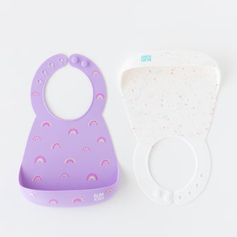 Bumkins Silicone Bib 2 Pack: Vanilla Sprinkle and Rainbows is neatly arranged on a white background.