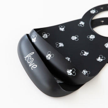 Close-up of Bumkins Silicone Bib 2 Pack: Disney Mickey and Minnie Mouse stacked on a white background.