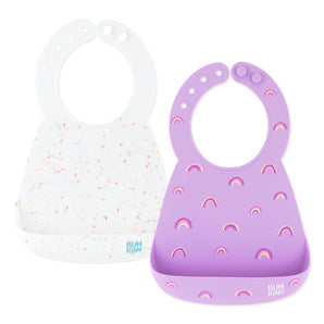 Bumkins Silicone Bib 2 Pack: Vanilla Sprinkle and Rainbows includes 2 silicone bibs with catch-all pockets; one in white and one in purple.