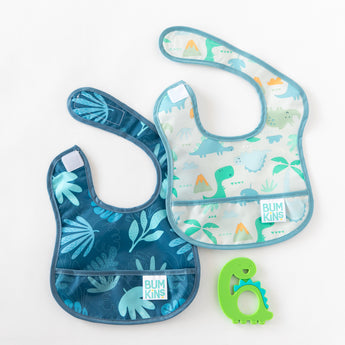 Two Bumkins Starter Bibs in Dinosaurs & Blue Tropic designs and green teether, crafted from waterproof fabric on a white background.