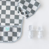 Bumkins Sleeved Bib: Charcoal Check next to baby utensils on a white background, ideal for baby-led weaning.