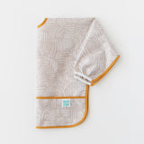 A bib from Bumkins On-The-Go Mealtime 6-Piece Set: Wander + Sand lays folded on a white background.