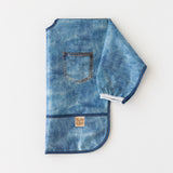A bib from Bumkins On-The-Go Mealtime 6-Piece Set: Denim + Blue lays folded on a white background.