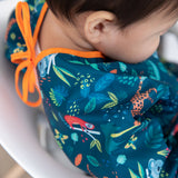 Closeup of the Bumkins Sleeved Bib: Jungle on a toddler near the tie closure.