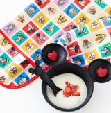 Bumkins Silicone First Feeding Set: Mickey Mouse Classic Black with yogurt & berries rests near a colorful Disney bib on a white background.