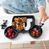 Close-up of a child's hand reaching for fruit & waffles from Bumkins Silicone Grip Dish: Mickey Mouse on a high chair tray.