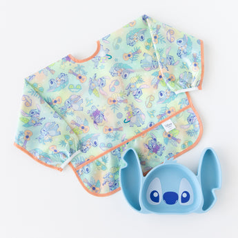 Bumkins Sleeved Bib: Aloha Stitch lays next to a Stitch-shaped silicone plate on a white background.