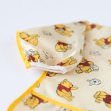 Close up of Bumkins Sleeved Bib: Winnie Loves Hunny on a white background, with focus on the white elastic cuff on the sleeve.