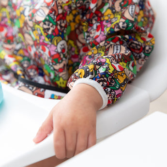 Close-up of a child's arm in a Bumkins Sleeved Bib: Super Mario™ Mashup, with focus on the elastic cuff of the sleeve.