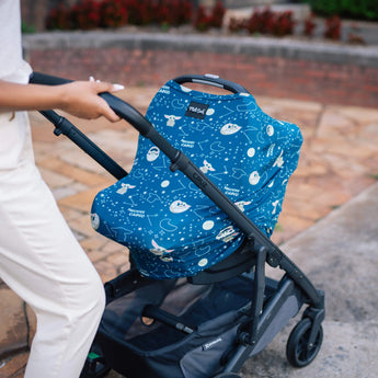 A person pushes a stroller with a Milk Snob Cover Star Wars the Child along a paved path.