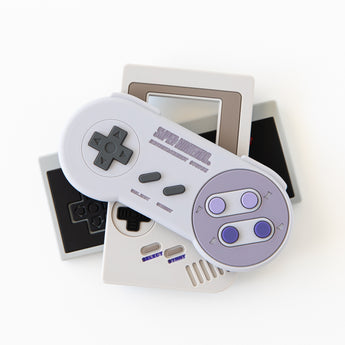 Bumkins Silicone Teether: Nintendo SNES™ Controller sits on top of other similar teethers on a white background.