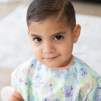 Close-up of a young boy wearing a Bumkins Junior Bib: Disney Aloha Stitch.