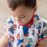 Close-up of a boy wearing a Bumkins Junior Bib: Super Mario™ & Luigi, looking down.