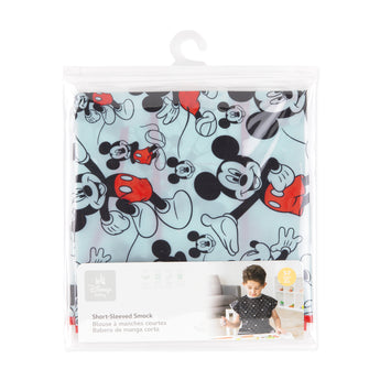 Bumkins Short-Sleeved Smock: Mickey Mouse Classic is shown folded in a plastic packaging bag with a hanger and cardboard insert.