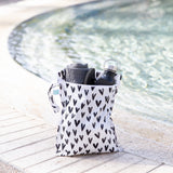 A black & white Bumkins Wet Bag 2 Pack: Gray Arrow and Hearts holds a towel, shoes, and a water bottle poolside.