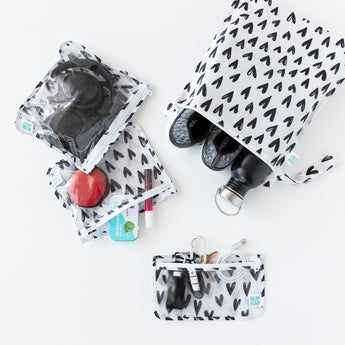 The Bumkins Chaos Coordinator Essential 4-Piece Set: Hearts holds keys, headphones, toiletries, a bottle & shoes on a white background.