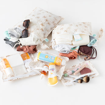 Bumkins The Chaos Coordinator Deluxe 5-Piece Set: Palm Daze holds travel essentials like swimwear, toiletries, and clothes on white.