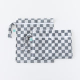 Two bags from Bumkins The Chaos Coordinator Deluxe 5-Piece Set: Charcoal Check lay overlapped on a white background.