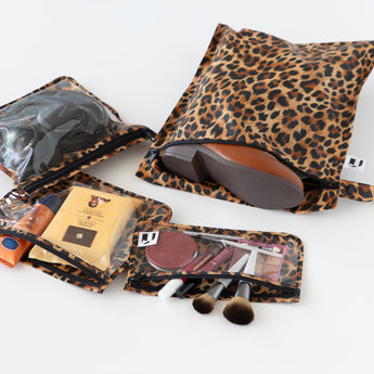 Roamio by Bumkins The Commuter Essential 4-Piece Set: Leopard holds shoes, makeup, and headphones on a white background.