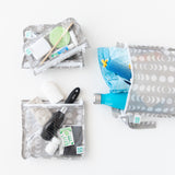Bags from Bumkins The Chaos Coordinator Deluxe 5-Piece Set: Lunar Phase hold toiletries, swim trunks, & water bottle on a white background.