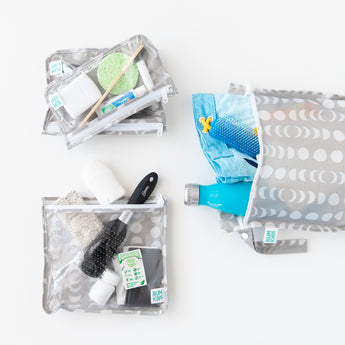 Bags from Bumkins The Chaos Coordinator Deluxe 5-Piece Set: Lunar Phase hold toiletries, swim trunks, & water bottle on a white background.