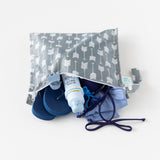 Bumkins Wet Bag: Arrow rests on a white background with flip-flops, a swimsuit, hair clip, and sunscreen inside.