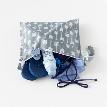 Bumkins Wet Bag: Arrow rests on a white background with flip-flops, a swimsuit, hair clip, and sunscreen inside.