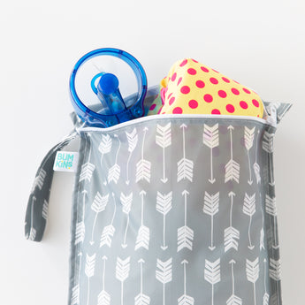 Bumkins Wet Bag: Arrow holds a yellow & pink polka dot swimsuit and a blue fan on a white background.