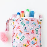 Travel size toiletries peek out of an open bag from Bumkins Wet Bag + Wet/Dry Bag Set: Boots on a white background.