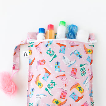 Travel-size toiletries peek out of a bag from Bumkins The Chaos Coordinator Deluxe 5-Piece Set: Boots on a white background.