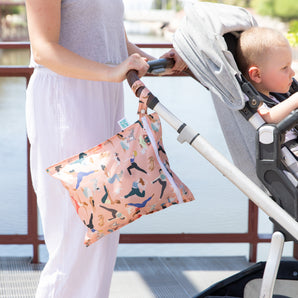 Person pushing a stroller with a baby, using the Bumkins Wet Bag + Wet/Dry Bag Set: Yoga Pals as a stylish, practical essential.