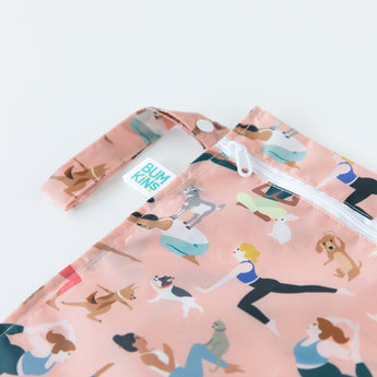 Close-up of Bumkins Wet Bag: Yoga Pals on a white background, with focus on the side handle, zipper, and logo label.