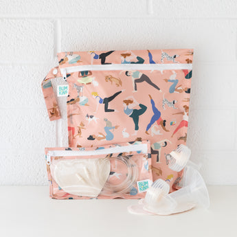 Bumkins Wet Bag: Yoga Pals sits on a white table against a white brick wall, with breast pump parts and a matching bag in front.