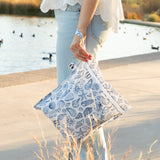 A woman stands on a concrete path by a pond with ducks, holding a Roamio by Bumkins Wet Bag: Shells.