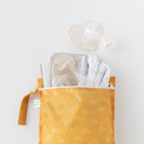 A yellow bag from Bumkins Wet Bag 2 Pack: Wander and Sunshine  holds breast pump parts and cloths on a white background.