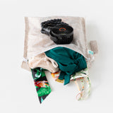 Bumkins Wet Bag: Wander lays open on a white background with swimsuit & clothes inside; a black fan lays on top.